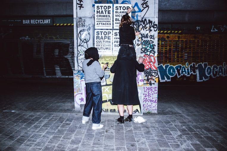 Drie jonge vrouwen trekken anoniem de straat op om affiches op te hangen. Beeld Francis Vanhee