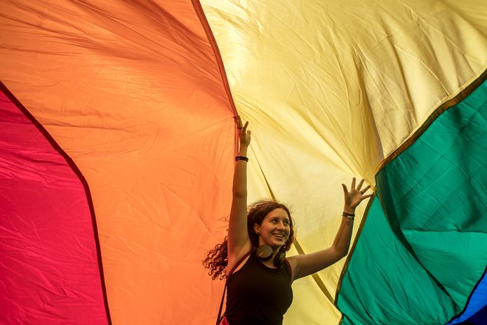 Een vrouw loopt onder een grote regenboogvlag tijdens een Gay Pride Parade in Praag.