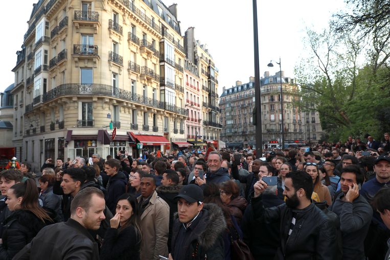 Mensen kijken toe terwijl de Notre Dame in brand staat. Beeld Getty Images