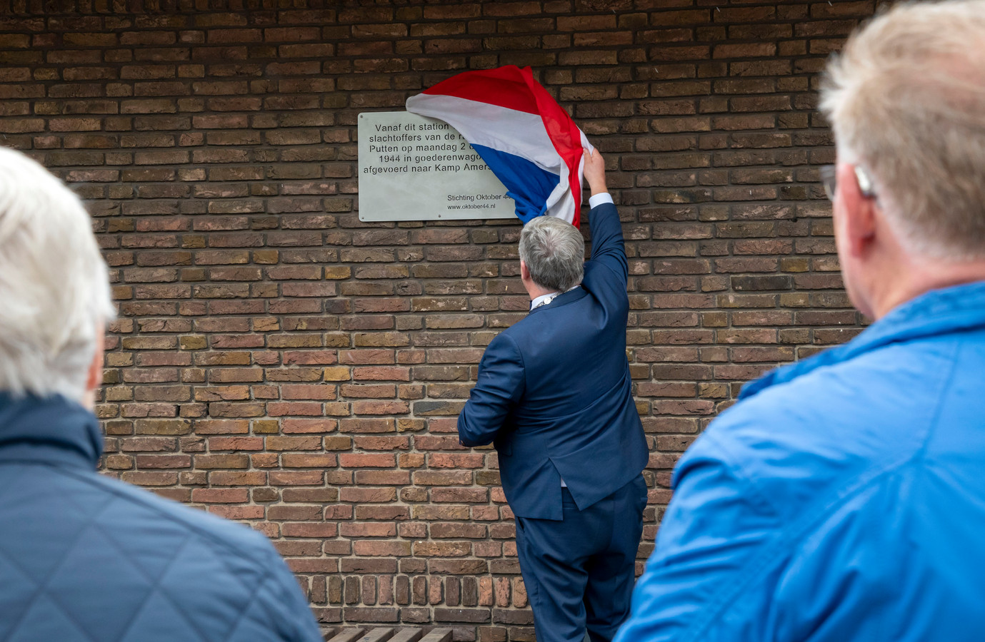 Burgemeester Henk Lambooij onthult de plaquette ‘De laatste ontbrekende schakel’ bij treinstation Putten ter nagedachtenis aan de razzia in 1944.