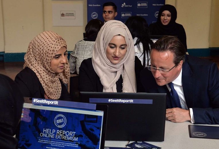 De Britse premier David Cameron bekijkt met Aysha Iqbal Patel (L) and Zahra Qadir een laptop tijdens een workshop over het rapporteren van verdacht gedrag online. Beeld afp