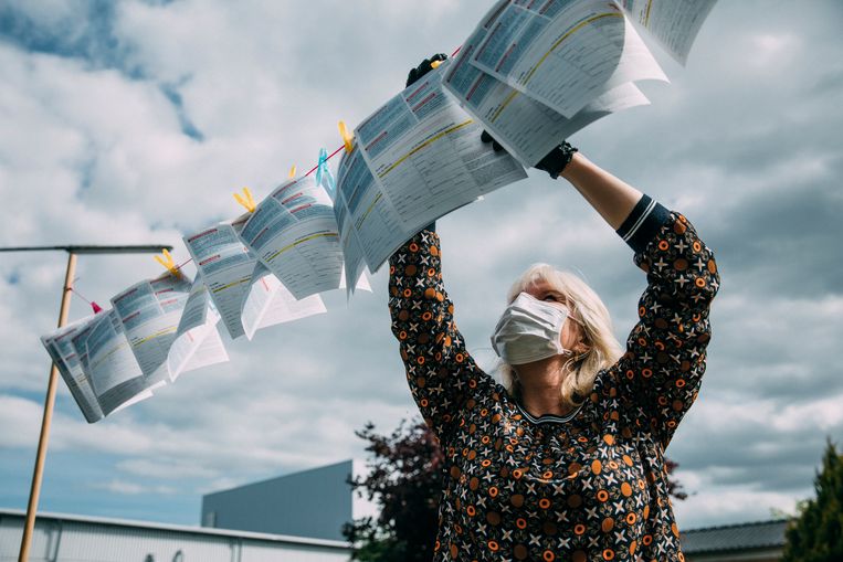 Een vrouw met flyers bij de fabriek van Tönnies in Kellinghusen. Op de flyers staat informatie voor contractarbeiders, veelal Roemenen. Het idee is dat ze na hun dienst een flyer kunnen pakken, maar de busjes waarin ze worden weggereden stoppen daar niet voor. Beeld Marlena Waldthausen 