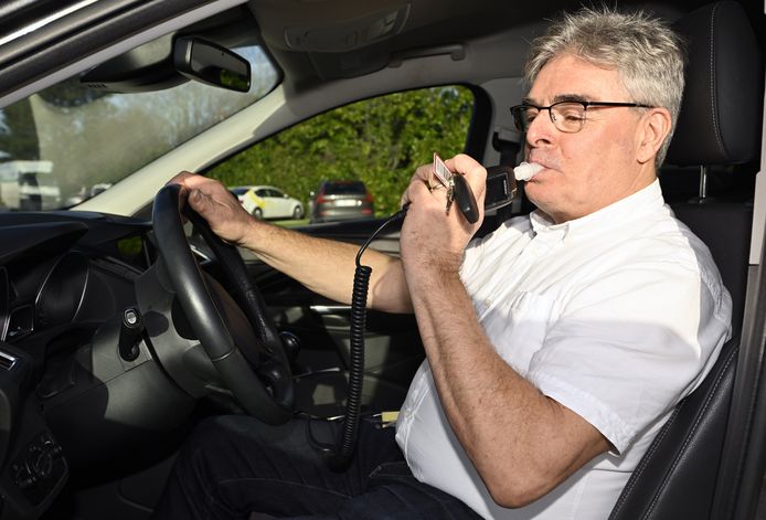 Een man doet een blaastest in de auto.