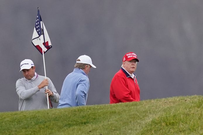 Donald Trump (in het rood) tijdens een potje golf gisteren.