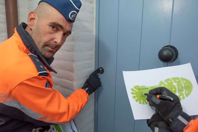 Een wijkinspecteur wijst op een deur die niet inbraakveilig is omdat het cilinderslot uitsteekt (foto uit archief).