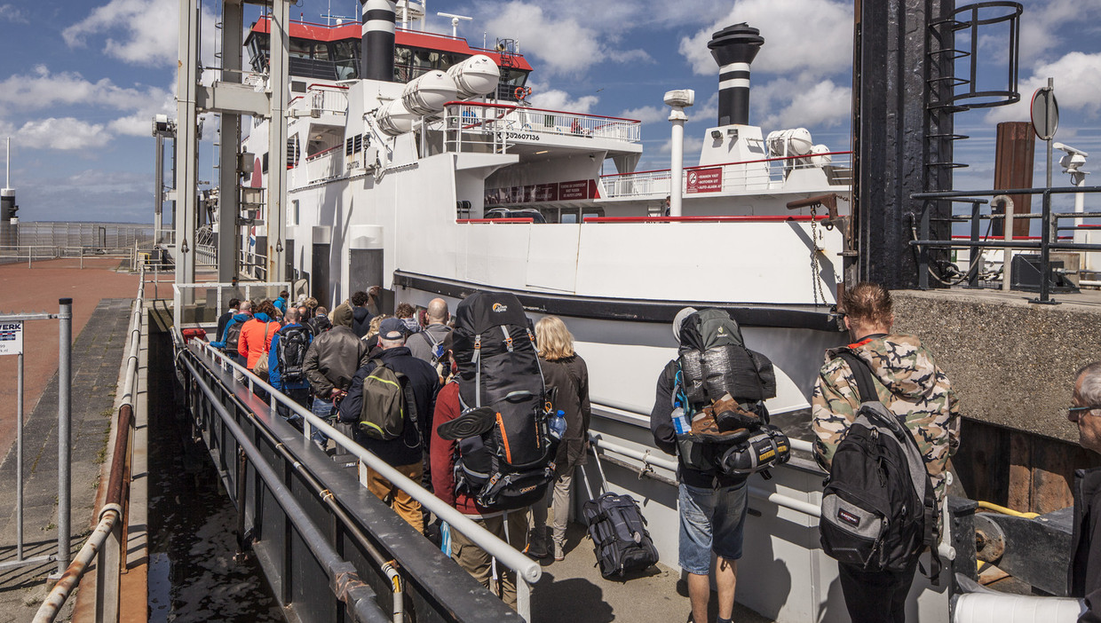 In het Friese Holwerd schepen reizigers naar Ameland zich in op een schip van Wagenborg. Beeld Harry Cock