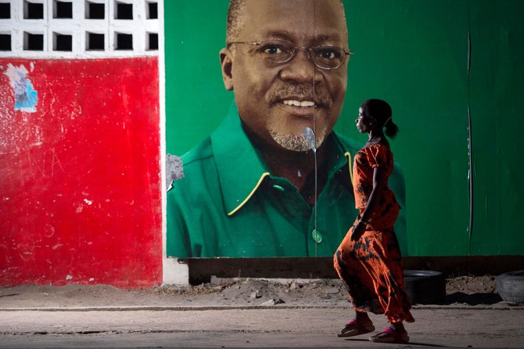 Een vrouw loop langs een verkiezingsaffiche van John Magufuli. In zijn strijd tegen wanbestuur ontsloeg de president al veel functionarissen. Beeld Daniel Hayduk