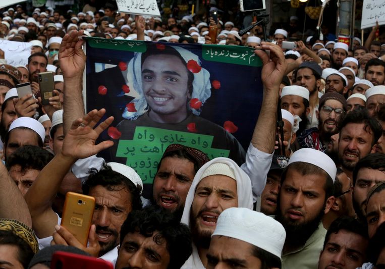 Aanhangers van een religieuze groepering houden een bord omhoog met daarop de foto van de tiener die Tahir Naseem vermoorde. Beeld AP