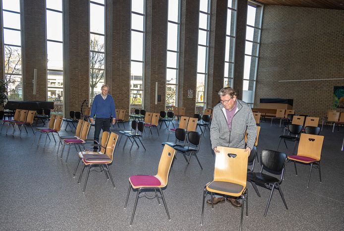 Douwe Klein en Johan Neuteboom (rechts) zetten de stoelen op hun plek in de kerkzaal van De Hoofdhof in Berkum.