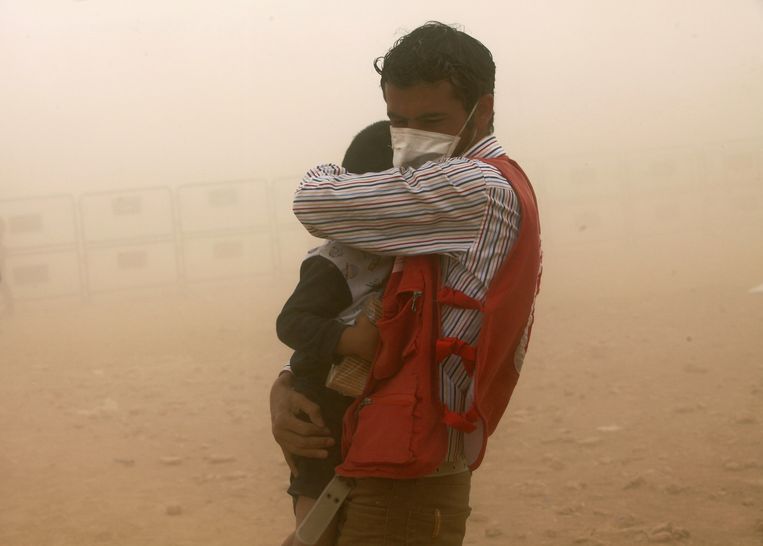 Een Turkse hulpmedewerker beschermt een Syrische vluchteling uit Kobani tegen een zandstorm Beeld ap