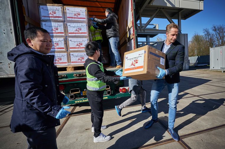 Minister Hugo de Jonge neemt in maart 2020 de eerste doos met mondkapjes in ontvangst van Steven Cai (Huawei). Het telecommunicatiebedrijf doneerde 800.000 mondmaskers.  Beeld ANP Handouts