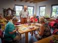 Cor van Dalen bij een tafel in De Minkhof waar deelneemsters aan het schilderen zijn.