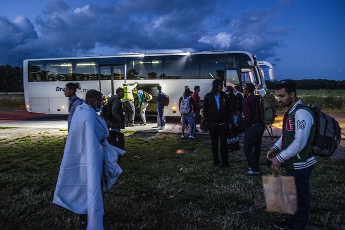 Asielzoekers bij het aanmeldcentrum worden met een bus naar een noodopvang elders in het land gebracht.