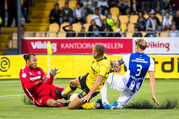 Johnatan Opoku zet op het kunstgras van De Koel een sliding in. Daniel Hoegh en Heerenveen-keeper Warner Hahn proberen hem af te stoppen.
