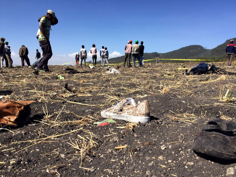 Op de plek waar het Ethiopische vliegtuig is neergestort, lopen mensen tussen de brokstukken.  Beeld REUTERS
