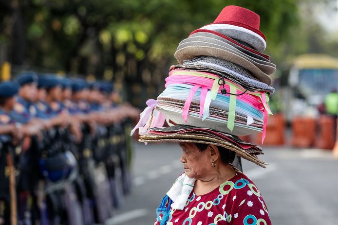 Een vrouw draagt haar koopwaar op haar hoofd tijdens een feestelijke  ceremonie in het Filipijnse Quezon City. Foto Mark R. Cristino