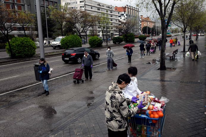 Mensen schuiven aan voor een supermarkt in Madrid; ze laten voldoende afstand tussen.