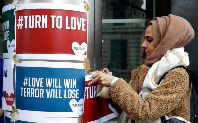 Demonstrant hangt bij het Nieuw-Zeelandhuis in Londen pamfletten op tegen de moord op moslims in Nieuw-Zeeland.  Beeld AP Photo/Kirsty Wigglesworth