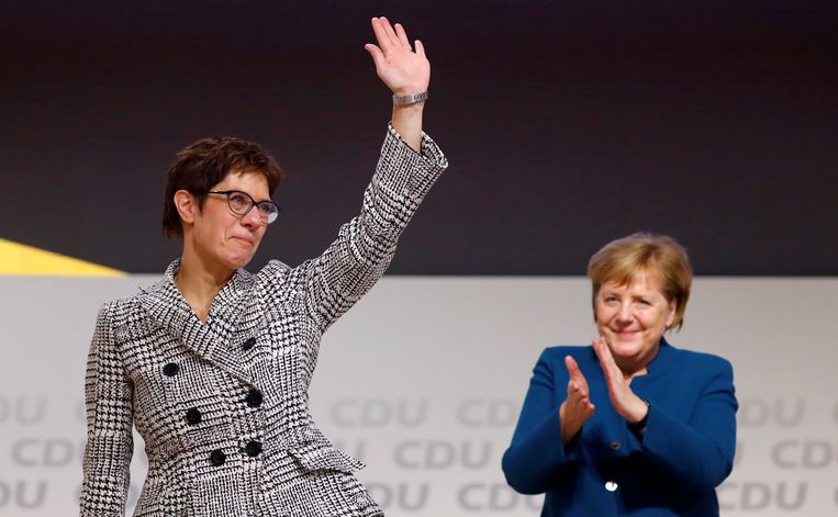 Annegret Kramp-Karrenbauer neemt op het podium het applaus van het congres in ontvangst als nieuw gekozen voorzitter van de CDU. Angela Merkel, nog wel bondskanselier, doet een stapje terug. Beeld REUTERS