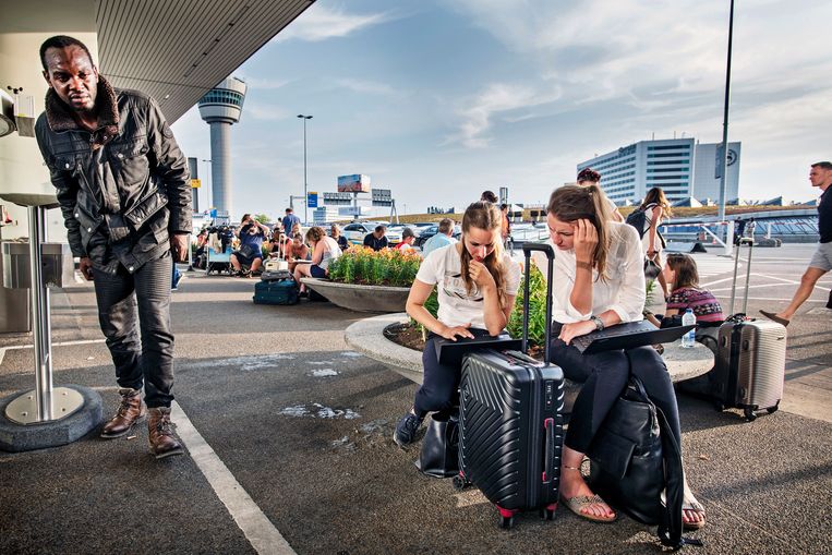 Reizigers die zijn gestrand door problemen op Schiphol met de kerosinetoevoer zoeken naar oplossingen op internet buiten de vertrekhal 2. 
 Beeld Guus Dubbelman / de Volkskrant
