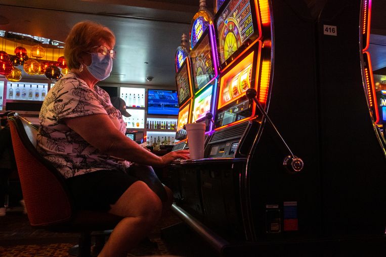 Een vrouw bij een gokautomaat in Las Vegas. Binnen en in alle openbare ruimtes in Las Vegas moeten mensen mondkapjes dragen. Beeld Eline van Nes