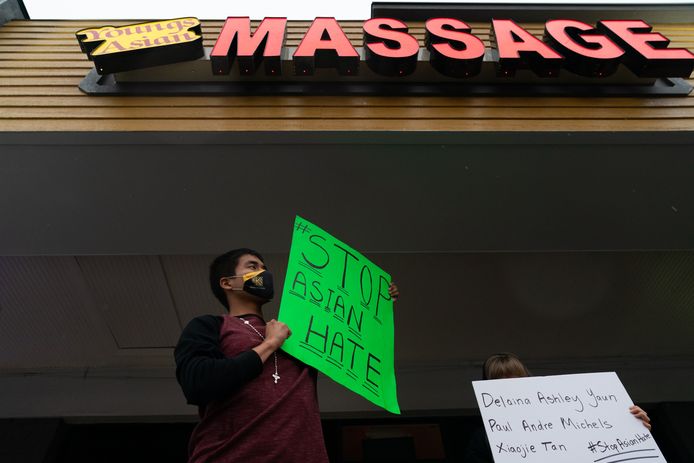Een man houdt een boord omhoog met de tekst 'stop haat jegens Aziaten' bij een van de aangevallen massagesalons.