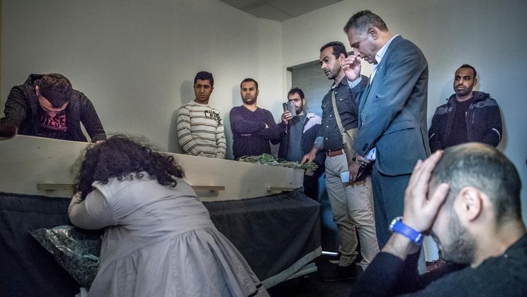 Mensen rouwen bij de Ranjoori's kist in het mortuarium van Schiphol. Zijn Iraanse kennissen kunnen niet geloven dat hij zelf voor de dood heeft gekozen. Beeld Marlena Waldthausen