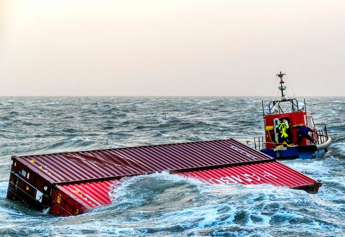 Een sleepboot brengt twee overboord geslagen containers van het schip MSC Zoë de haven binnen