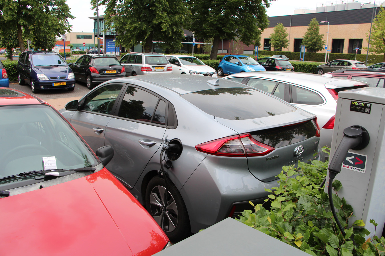 Elektrische auto en foutgeparkeerde benzineauto bij elektrisch laadpunt bij gemeentehuis Berkelland.