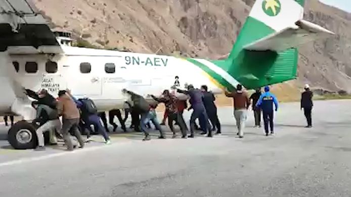Des passagers poussent un avion hors de la piste d'atterrissage.