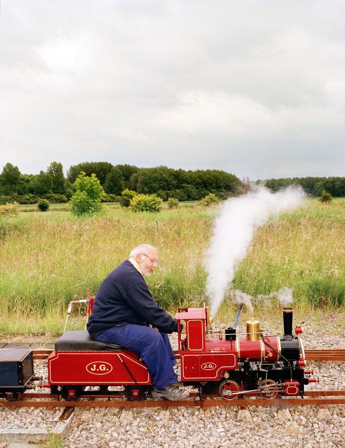 Machinist Jan Gravemaker op zijn rode locomotief op de 'Stoomdag' van modelbouwvereniging Het Y in Velsen Zuid. In de zomer rijden ze zondagmiddag rondjes op hun eigen parcours vlakbij Spaarnwoude. 
Uit de serie 'Mannen van de Modelbouw'.