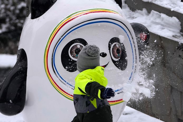 Een kind gooit een sneeuwbal naar pandabeer Bing Dwen Dwen, de mascotte van de huidige Olympische Winterspelen.
