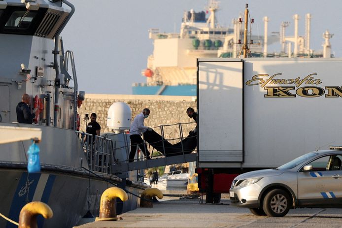Mannen brengen de lijkzakken met migranten die omkwamen nadat hun boot kapseisde in open zee voor de kust van Griekenland, over aan boord van een vaartuig van de Griekse kustwacht in de haven van Kalamata.
