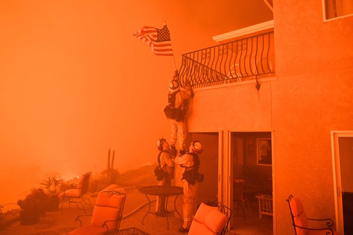 Brandweerlieden redden tijdens bosbranden in Californië een vlag van een huis.