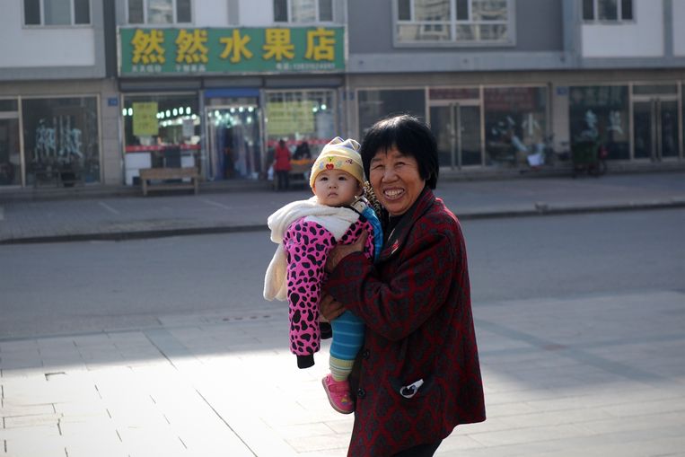 Een vrouw wandelt met baby over straat in de noordelijke provincie Hebei. Door allerlei uitzonderingen hadden bepaalde groepen wel recht op een groter gezin.. Beeld AFP