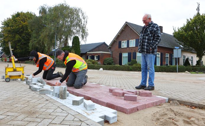 Gerard Verhoeven kijkt toe hoe werklui de fiets- en stopstrook leggen, die meer duidelijkheid moet geven op de beruchte kruising van Biezenmortel.