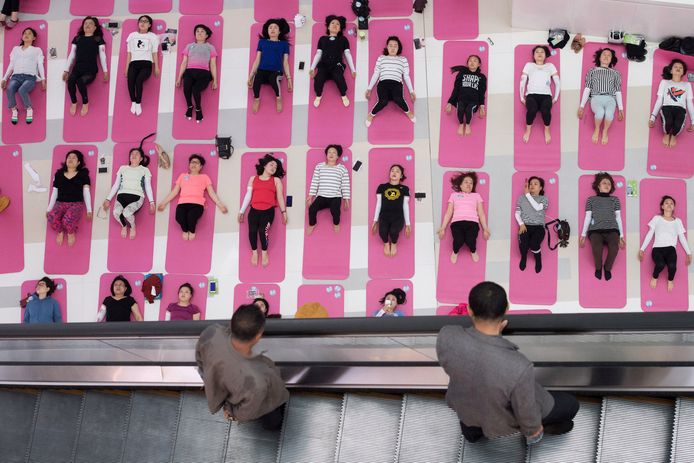 In het Chinese winkelcentrum in Taiyuan kijken voorbijgangers op een roltrap naar vrouwen die yoga oefeningen doen. Foto Stringer