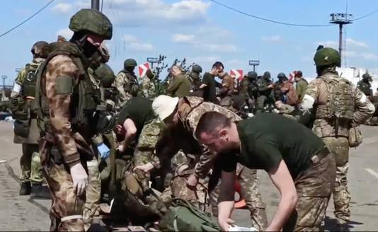 Op dit beeld uit een video verspreid door het Russische ministerie van Defensie worden Oekraïense soldaten die uit de Azovstalfabriek komen gefouilleerd door Russische soldaten.
