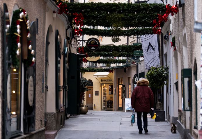 Een man wandelt met zijn hond door een lege winkelstraat in Salzburg.
