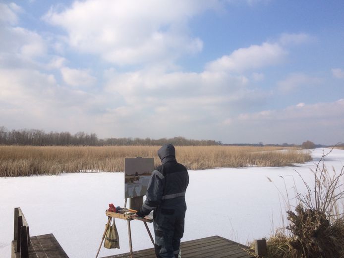 Een schilder legt het winterse landschap vast op doek. Hij schildert in de Zouweboezem in Ameide.