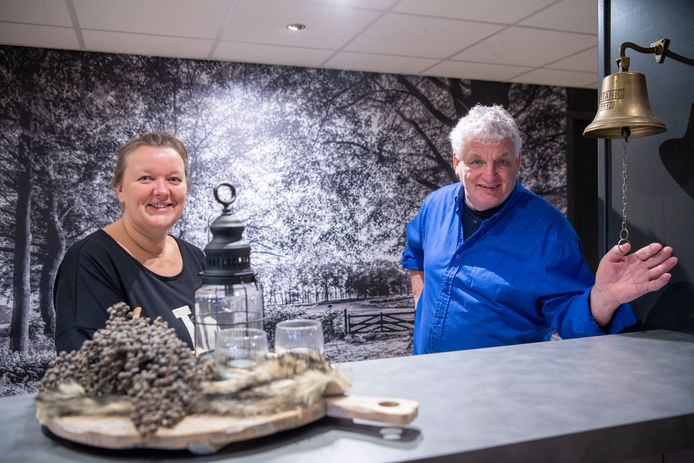 Petra van Haarst en Gerard Rietman achter de bar van de grote zaal van dorpshuis De Vilsterij. Op de achtergrond een grote zwart-wit foto van het stuwpad en de oude Vechtarm in Vilsteren.