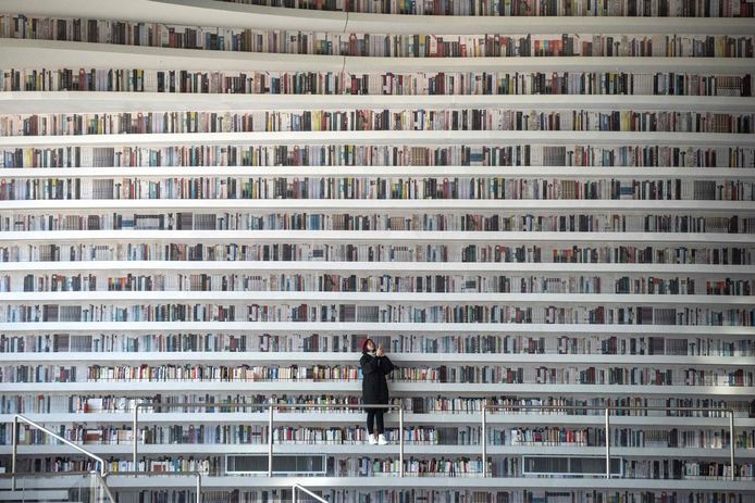 Een Chinese vrouw maakt foto’s in de Bibliotheek in Tianjin Binhai. Boekenliefhebbers over de hele wereld zijn verguld over de witte, golvende planken die van vloer tot plafond oprijzen. Foto Fred Dufour