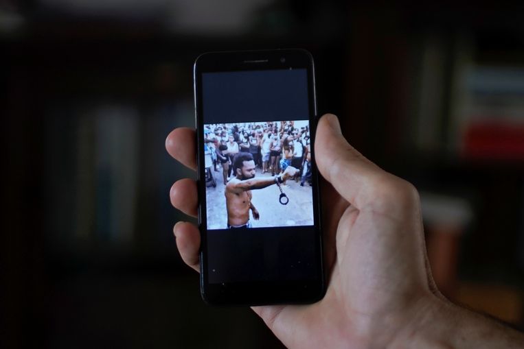 De rapper Maykel Osorbo, het bovenlijf ontbloot, steekt een vuist in de lucht. Aan zijn pols bungelt een handboei. Cuba wil de strijd tegen dergelijke dissidenten opvoeren.  Beeld REUTERS