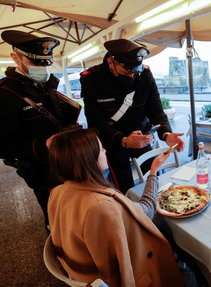 Un policier vérifie le pass sanitaire d'une personne dans un restaurant le jour où le gouvernement restreint l'accès aux personnes non vaccinées, à Naples, en Italie, le 6 décembre 2021.