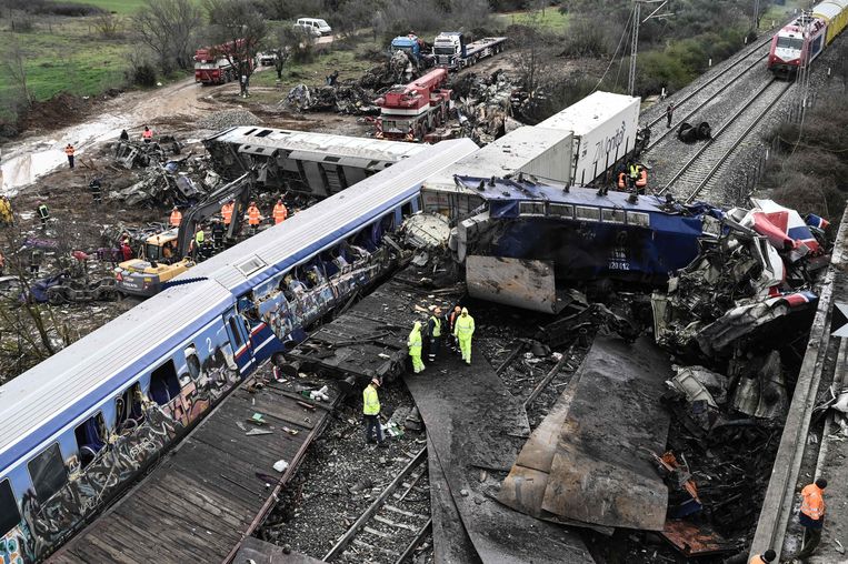 Politieagenten en reddingswerkers doorzoeken de wrakstukken van één van de wagons van de treinramp bij Tempi. Beeld AFP