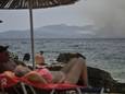 Zonnende toeristen in Albanië in juli 2023, terwijl even verderop op het Griekse eiland Corfoe bosbranden woeden.