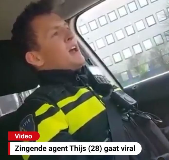 De jonge agent zingt vrolijk mee met de hit van Queen in de auto