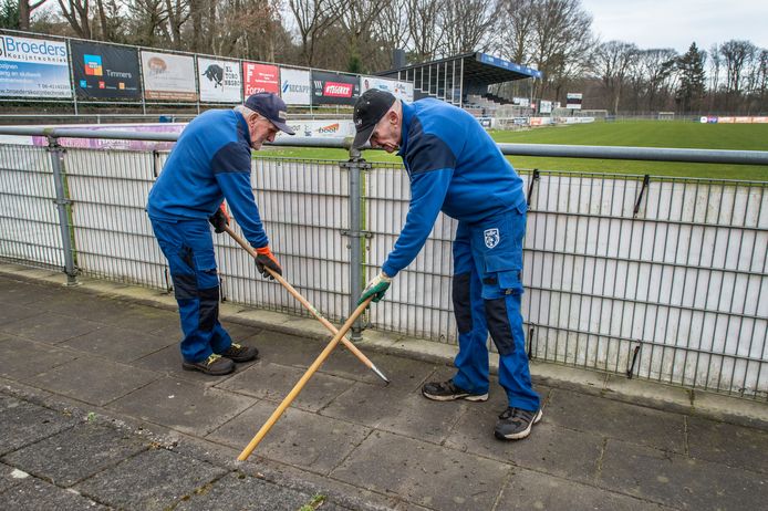 Kees Verduyn (l.) en Sjaak Snoek zijn bezig met het onkruid tussen de tegels te verwijderen.