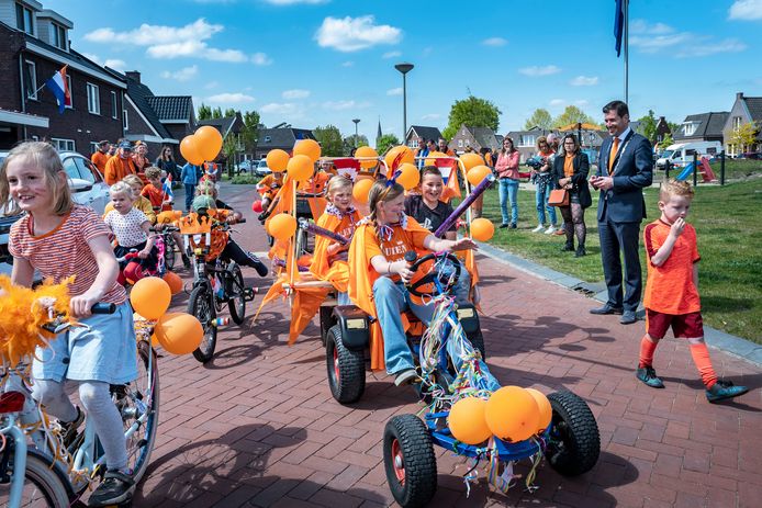 Kinderen gaan in Nederasselt van start met hun optocht met versierde fietsen, nadat burgemeester Joerie Minses (rechts) de vlag heeft gehesen en fanfare Wilhelmina het Wilhelmus heeft gespeeld.