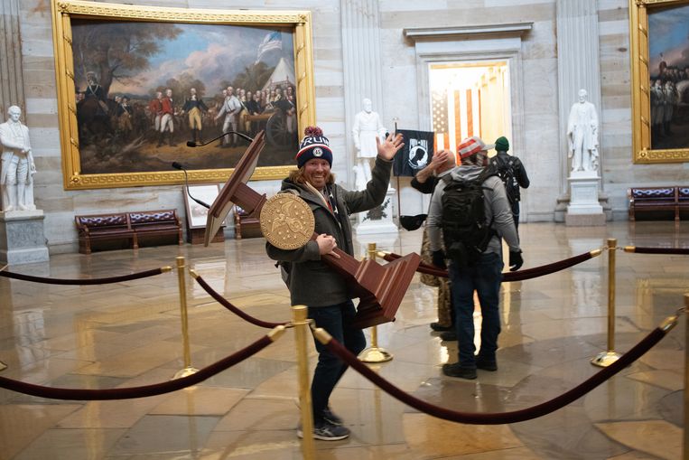 Een binnengedrongen Trumpaanhanger poseert met de katheder van Nancy Pelosi, de voorzitter van het Huis van Afgevaardigden. Beeld Getty Images